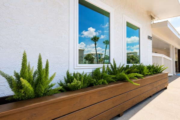 A building facade with large windows, a wooden planter with greenery, and a sign with the number '8010'. - Pet-Friendly with Gulf Views - Steps to St. Joe Beach – Flower Power (Port St Joe)