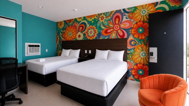 A hotel room with a large bed, two bedside tables, a desk, a chair, and a colorful floral wall. - Pet-Friendly with Gulf Views - Steps to St. Joe Beach – Flower Power (Port St Joe)