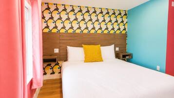 Una habitación de hotel con una cama, una mesita de noche, un cabecero de madera, un papel tapiz estampado y una pared roja.