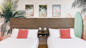 Quarto duplo com duas camas, cabeceira de madeira e mesa de cabeceira com telefone e carregador.