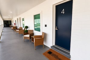 En hotellkorridor med en rad flätade stolar och en mörkblå dörr som är numrerad med 4.