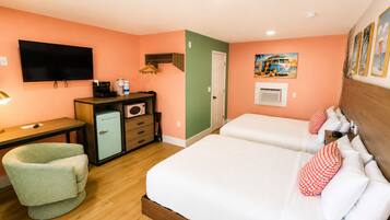 Habitación de hotel con cama, escritorio, silla, refrigerador, televisor y un cuadro en la pared.