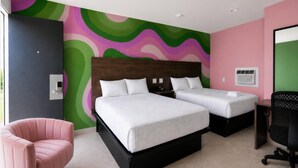 Une chambre d’hôtel avec deux lits, une chaise rose et un bureau avec une chaise.