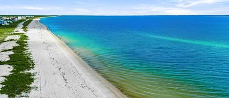 Une plage offrant une vue dégagée sur l’océan et bordée d’un rivage sablonneux.