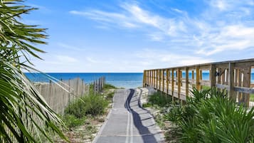 Une promenade en bois qui mène à une plage, avec un ciel dégagé.