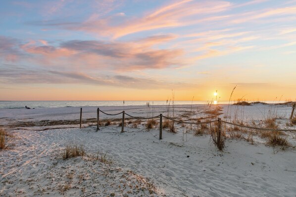 A beach with a rope barrier, sandy dunes, and the ocean.