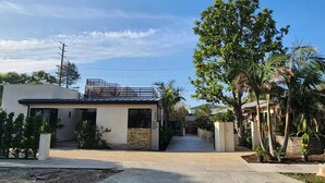 Une maison moderne à deux étages, dotée d’une allée pavée et d’un grand arbre dans le jardin avant.