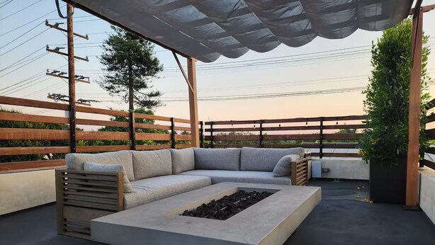 Une terrasse sur le toit avec un canapé d’angle, un foyer en béton et une pergola.