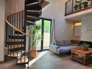 Un intérieur moderne avec un escalier en colimaçon, un canapé, une table basse et une plante en pot.