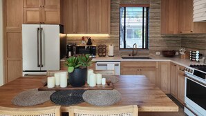 Une cuisine moderne avec des meubles en bois, un îlot central agrémenté de bougies et un mur d’accent en pierre.