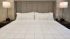 Une chambre d’hôtel avec un grand lit, deux tables de chevet et deux lampadaires.
