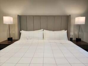 Habitació d'hotel amb un llit gran, dues taules de nit i dues làmpades de peu.