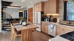 Une cuisine moderne avec des meubles en bois, un réfrigérateur en acier inoxydable et une cuisinière à gaz.