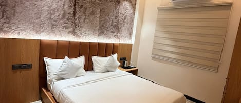 A modern bedroom with a bed, a ceiling fan, an air conditioning unit, and a window with blinds.