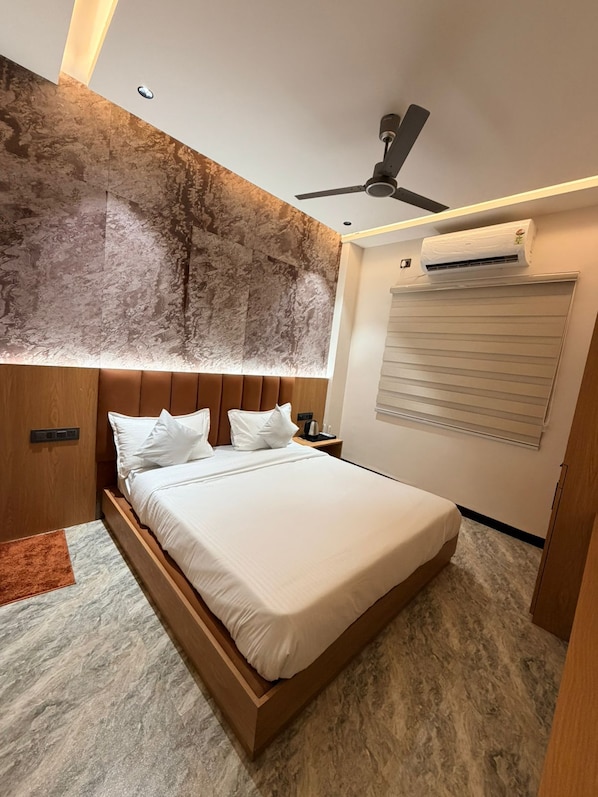 Un dormitorio moderno con cama, ventilador de techo, equipo de aire acondicionado y ventana con persianas.