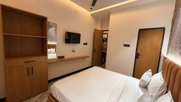 Un dormitorio moderno con una cama, armarios de madera, un televisor y un ventilador de techo.