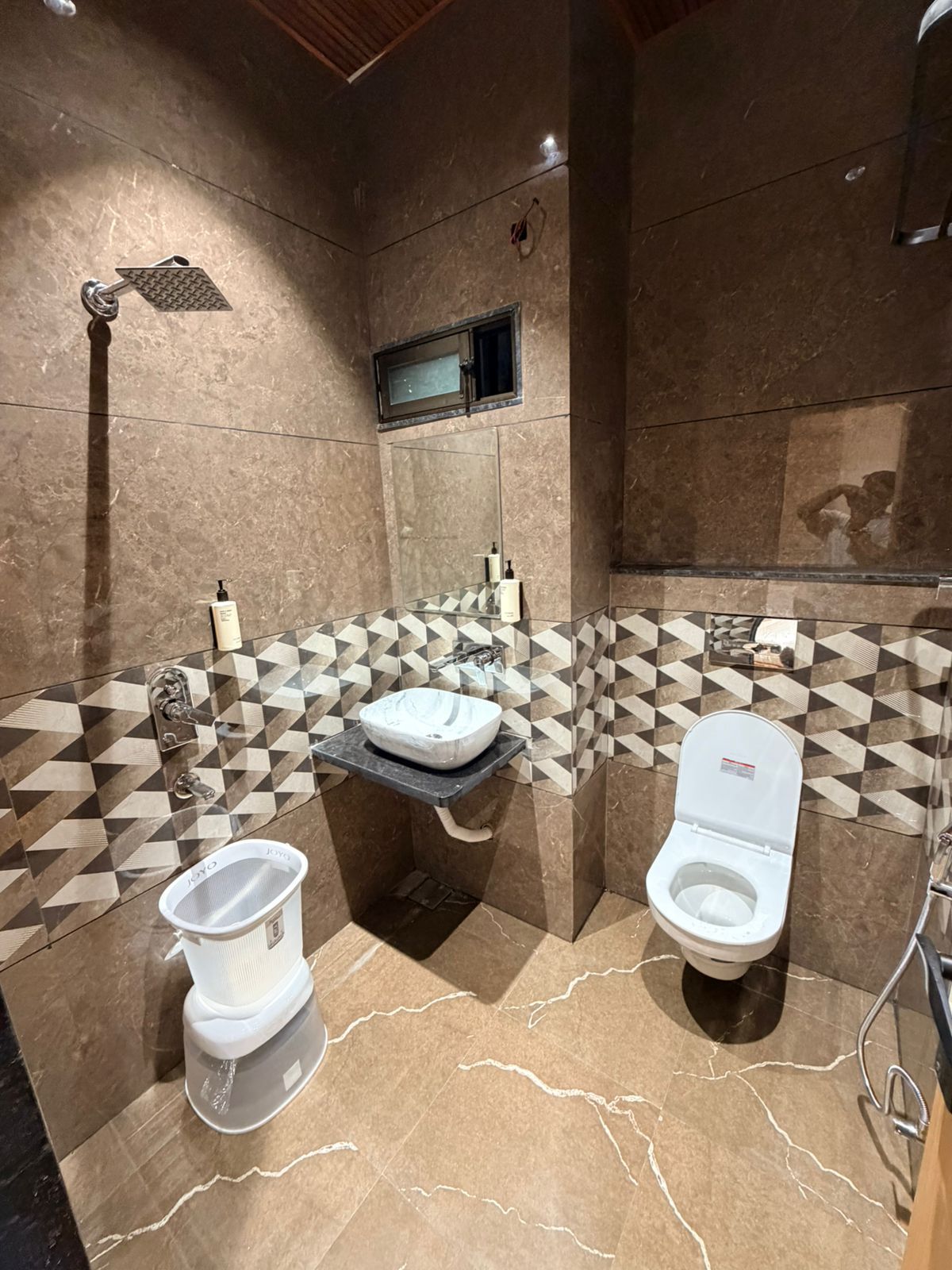 Uma casa de banho moderna com um espelho grande, duas sanitas, uma pia e um chuveiro.