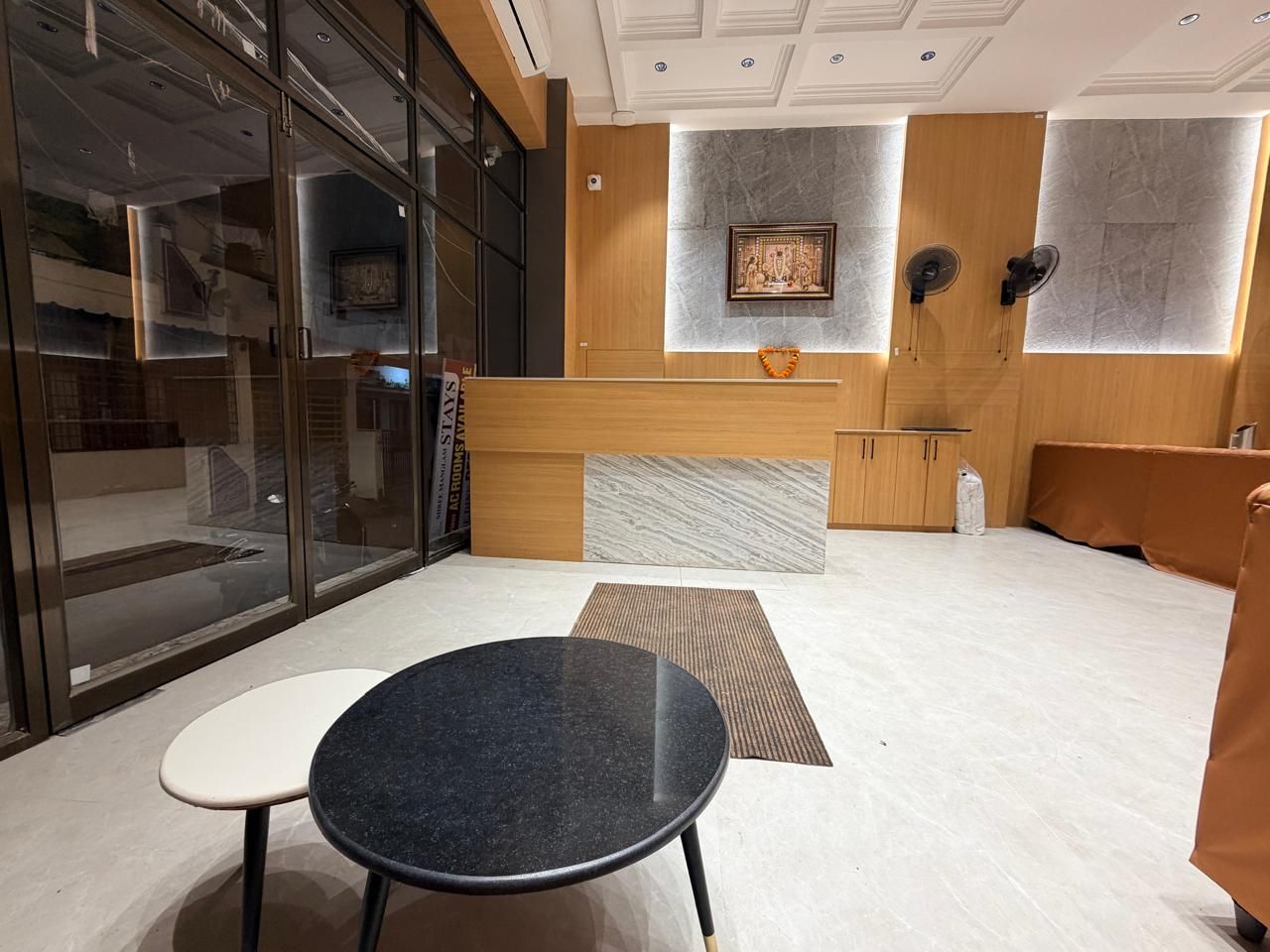 Um hall de hotel moderno com balcão de recepção, área de estar e uma grande janela.