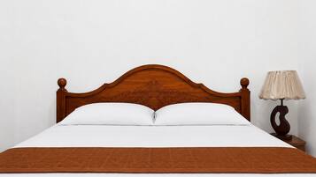 A bed with a wooden headboard, white bedding, and a brown throw blanket.