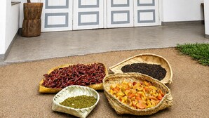 A room with a white door, a wooden bucket, and baskets of dried peppers and beans. - Piyasewana Spice Garden Villa (Banduragoda)