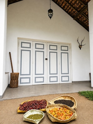 A room with a white door, a wooden bucket, and baskets of dried peppers and beans. - Piyasewana Spice Garden Villa (Banduragoda)