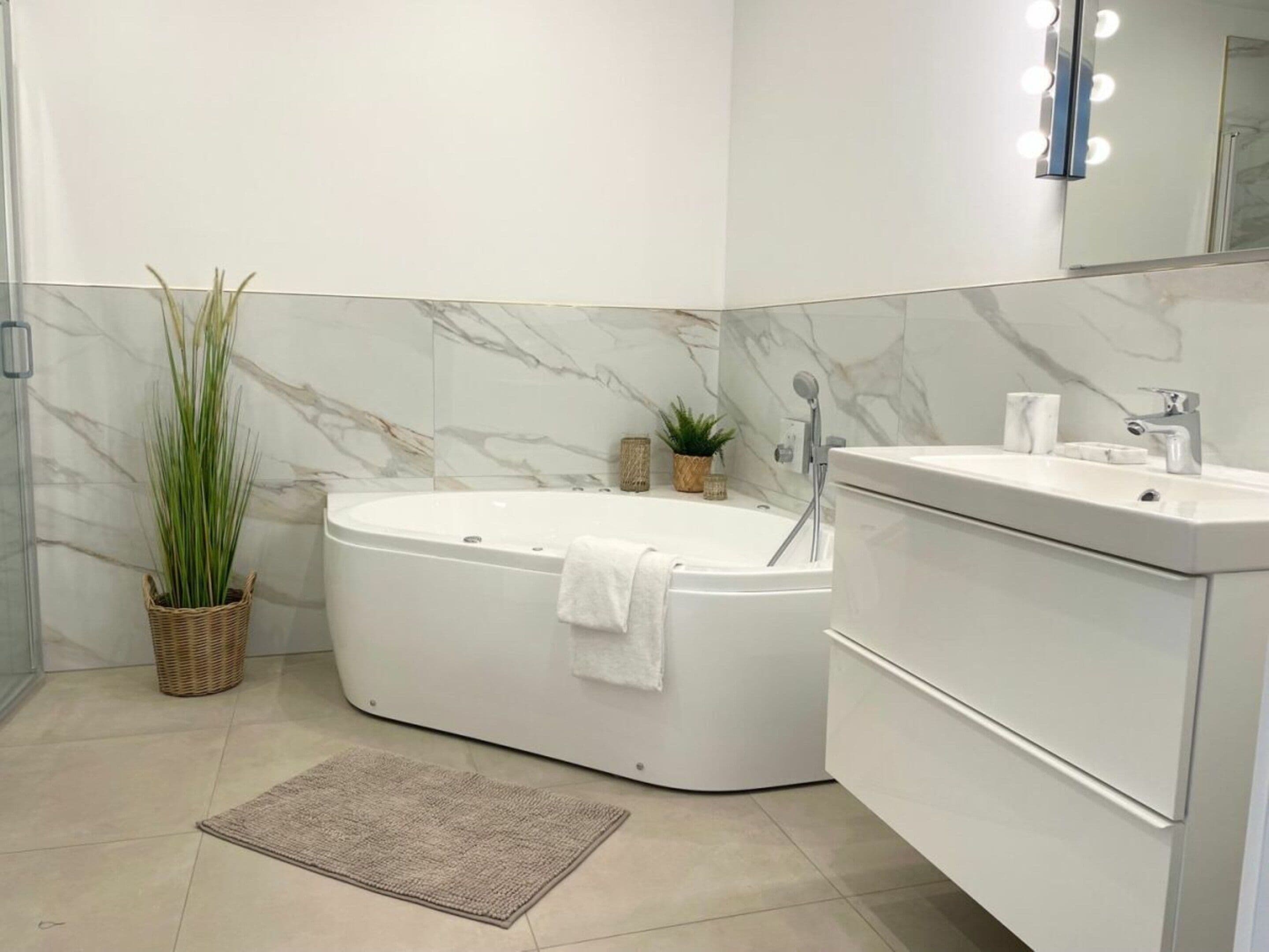 Une salle de bain moderne avec une baignoire sur pieds, un meuble-lavabo avec un miroir et une plante en pot.