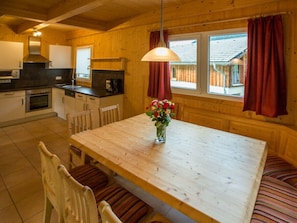 A wooden interior with a kitchen, dining table, chairs, and a vase of flowers. - Cabin in Annaberg With Swimming Pool (Annaberg-Lungoetz)