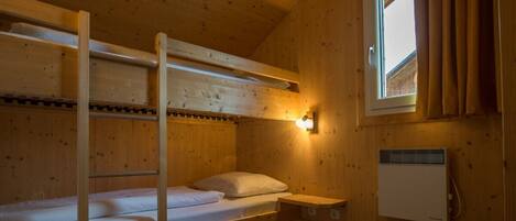 A bunk bed room with a window and a wall-mounted heater.