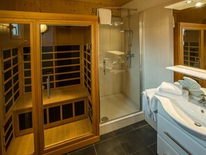 A modern bathroom with a glass-enclosed shower, a wooden sauna, and a white sink with towels. - Cabin in Annaberg With Swimming Pool (Annaberg-Lungoetz)