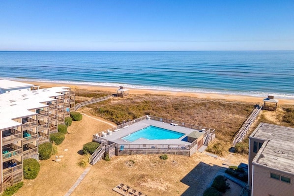 Um imóvel à beira-mar com piscina, edifícios de vários andares e vista para a praia.