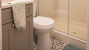 Een badkamer met toilet, wastafel met handdoek, spiegel en douchecabine.