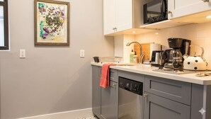 Een moderne keuken met grijze kastjes, een vaatwasser, een koffiezetapparaat en een magnetron.