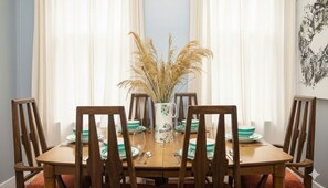 A dining table set with plates, cutlery, and a vase with dried plants. - Classic NYC 3BR/1BA City Escape! Stay Near Central Park! (New York)