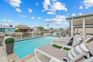 A swimming pool with lounge chairs and a dock extending into the water. - Hook, Wine and Sinker ~3 Bed / 2 Bath Home with a Pool! (Rockport)