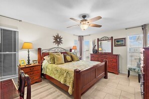 A bedroom with a wooden bed, two bedside tables with lamps, a dresser, a chair, and a ceiling fan. - Hook, Wine and Sinker ~3 Bed / 2 Bath Home with a Pool! (Rockport)