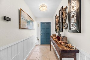 A hallway with a blue door, a wooden bench with decorative items, and wall art. - Hook, Wine and Sinker ~3 Bed / 2 Bath Home with a Pool! (Rockport)