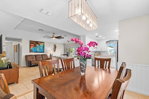 A spacious dining area with a wooden table, chairs, and a vase of flowers. - Hook, Wine and Sinker ~3 Bed / 2 Bath Home with a Pool! (Rockport)