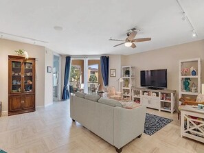 A living room with a sofa, television, and a ceiling fan. - Spacious 3-bedroom condo with AC in peaceful Vero Beach (Vero Beach)