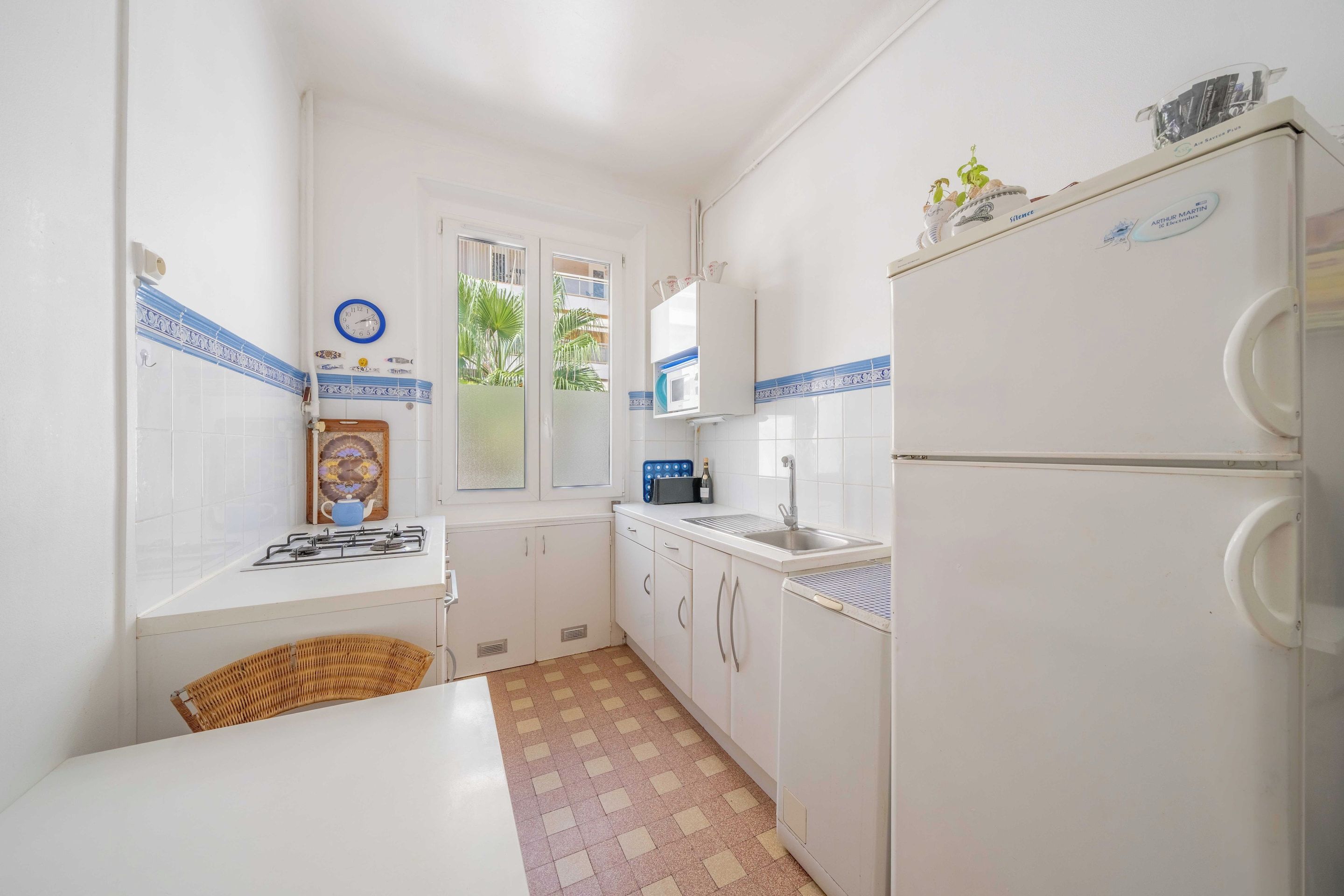 A compact kitchen with white cabinets, a gas stove, a sink, and a refrigerator.