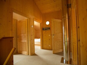 A wooden interior with a bed in the background, a door with a round light, and a metallic object on the floor. - Cabin in Annaberg With Swimming Pool (Annaberg-Lungoetz)