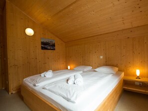 A wooden room with a bed, two bedside lamps, and a painting on the wall. - Cabin in Annaberg With Swimming Pool (Annaberg-Lungoetz)