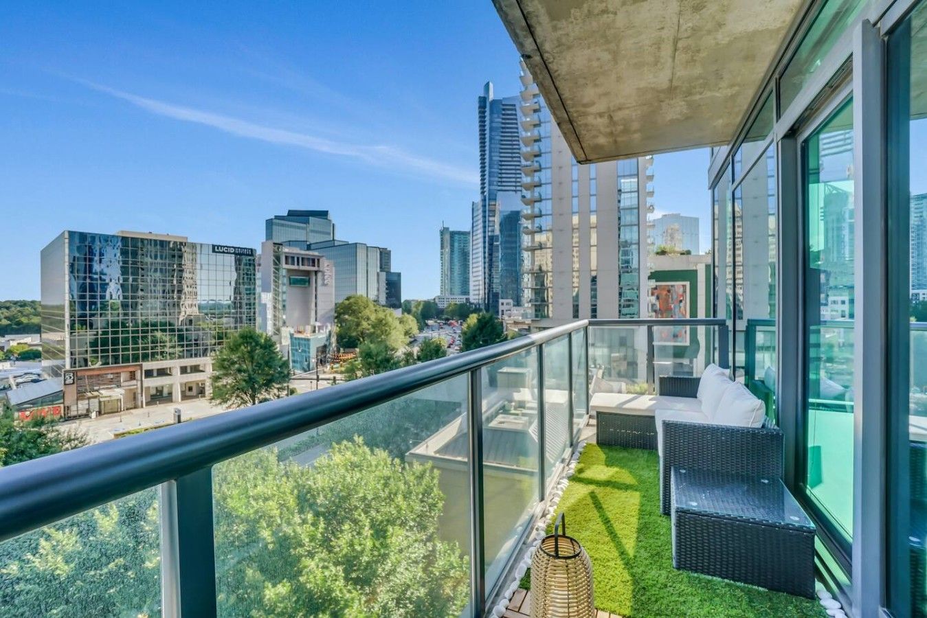 Ein Balkon mit Blick auf eine Stadtlandschaft, darunter moderne Gebäude und eine Grünfläche.