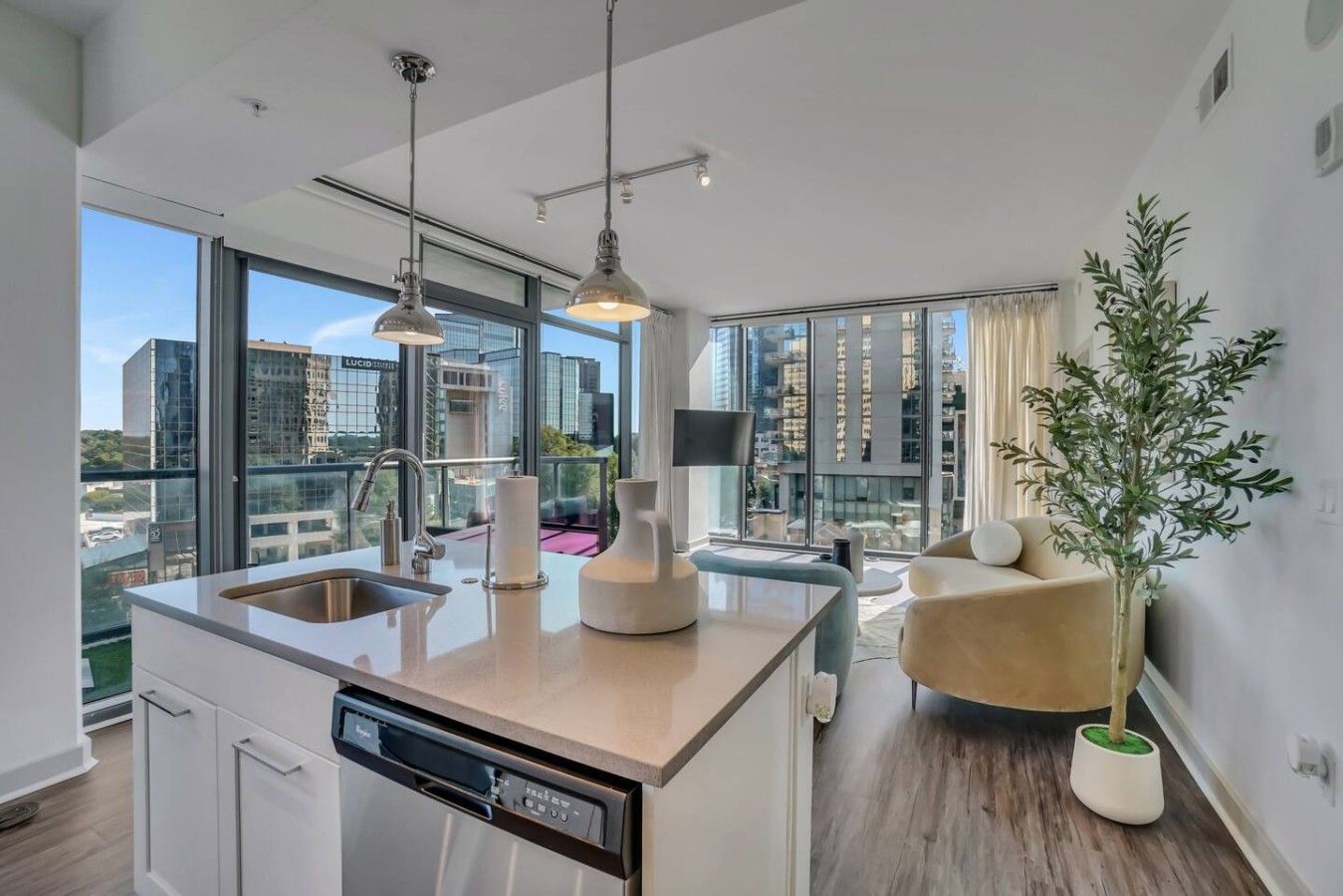 Una cocina moderna con lavavajillas, un lavabo y un comedor con una silla y una planta.
