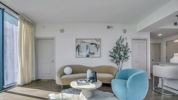 Un soggiorno moderno con un divano, una poltrona blu, un tavolino da caffè, un quadro e una pianta in vaso.