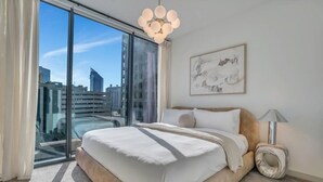 Una camera da letto moderna con un letto grande, vista sulla città e arredamento minimalista.