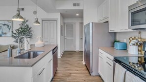 Una cucina moderna con elettrodomestici in acciaio inossidabile, mobili bianchi e pavimento in legno.