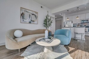 Una sala de estar moderna con un sofá color beige, un sillón azul y una mesita de centro con un libro.