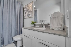 Un baño con un lavamanos blanco, un espejo, un perchero para toallas y un inodoro.