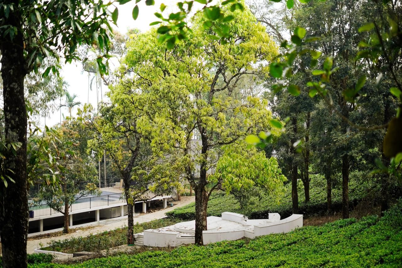 Un parque con árboles, una estructura circular blanca y un edificio con techo.