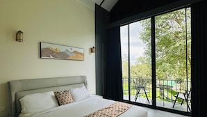 A modern bedroom with a large bed, a painting, and a view of the outdoors through a sliding door. - WAYANAD DE MOUNT RESORT BY RAK ROOMS (KL)